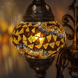 Lit close-up of mosaic glass globe — Amber wall sconce glowing (ENV APN2079)