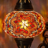 Lit close-up of mosaic glass globe — Amber wall sconce glowing (ENV APN3011)