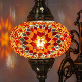 Lit close-up of mosaic glass globe — Amber wall sconce glowing (ENV APN3065)