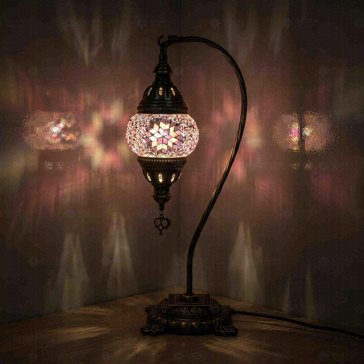 Pink Star Swan Neck Table Lamp, switched on, glowing in a dark room