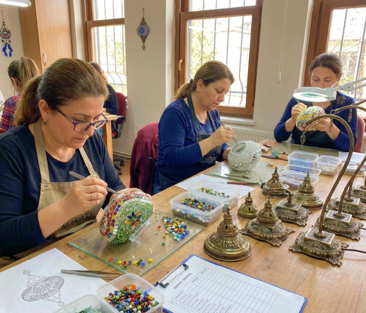 Artisans setting glass pieces onto lamp globes in our workshop in Türkiye